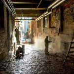 workers cleaning graffiti from concrete walls